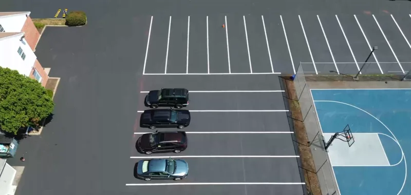 Wide-angle view of freshly sealcoated commercial parking lot showing full scale