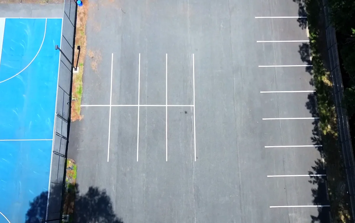 Faded and deteriorating commercial parking lot showing worn striping and surface damage