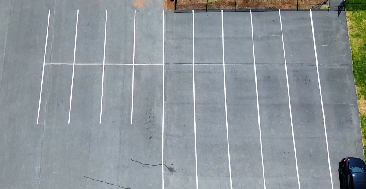 Parking lot with faded barely-visible striping before line striping service